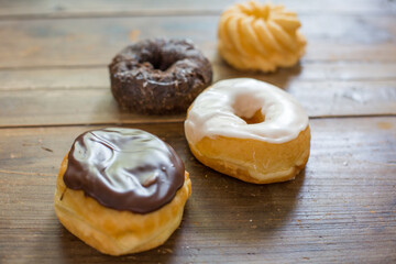 Bakery fresh doughnuts soft and sweet delicious glazed frosted donuts variety on wood table surface
