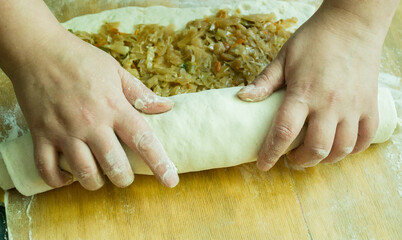 A woman rolls meat with cabbage into a roll. Homemade baking.