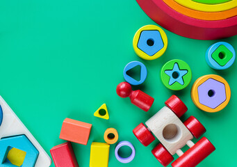 Wooden toys, arc, cubes, brushes on green background. Back to school background. Close up. Top view, copy space. Educational games for kindergarten, preschool kids