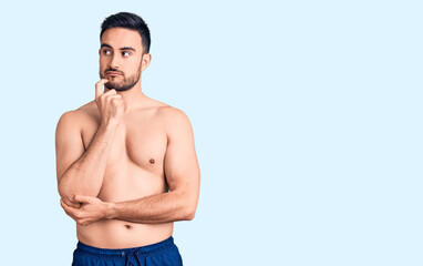 Young handsome man wearing swimwear serious face thinking about question with hand on chin,...