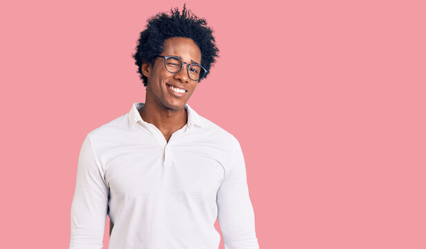 Handsome african american man with afro hair wearing casual clothes and glasses winking looking at the camera with sexy expression, cheerful and happy face.