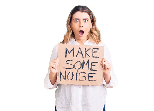 Young caucasian woman holding make some noise banner scared and amazed with open mouth for surprise, disbelief face