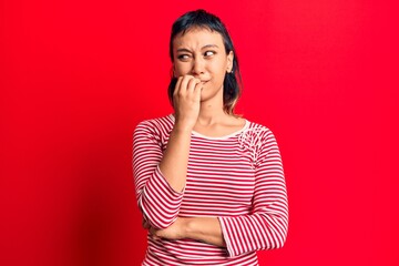 Young woman wearing casual clothes looking stressed and nervous with hands on mouth biting nails. anxiety problem.