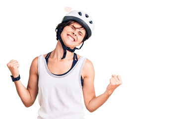 Beautiful young woman with short hair wearing bike helmet very happy and excited doing winner gesture with arms raised, smiling and screaming for success. celebration concept.