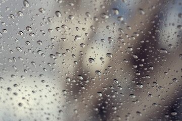 Rain drops on a glass window as an abstract blurred background. Selective focus.