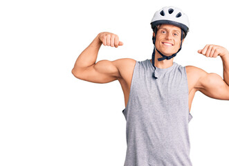 Young handsome man wearing bike helmet showing arms muscles smiling proud. fitness concept.