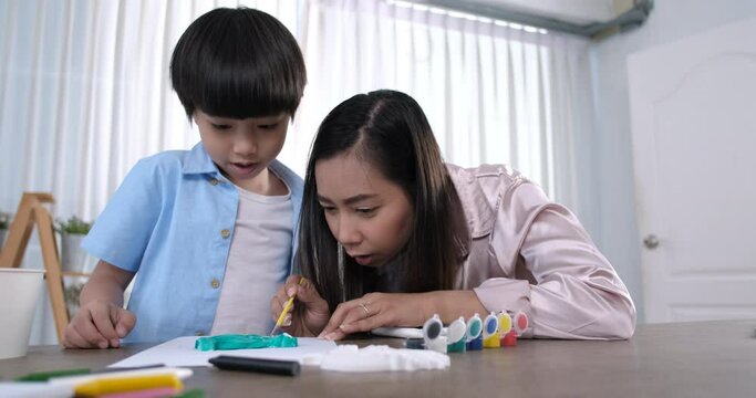 Happy asian mother and little son together paint. Happy mother and daughter are having fun while drawing at home. Lifestyle family moment.