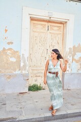 Beautiful young woman wearing fashionable clothes walking down the street