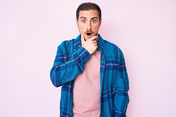 Fototapeta premium Young handsome man wearing casual clothes looking fascinated with disbelief, surprise and amazed expression with hands on chin