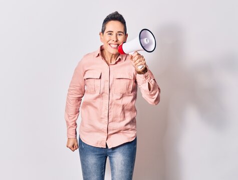 Young beautiful caucasian woman screaming using megaphone. Jumping over isolated white background