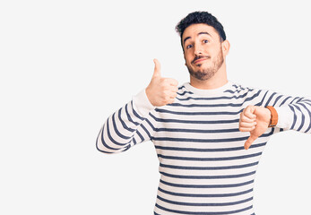Fototapeta premium Young hispanic man wearing casual clothes doing thumbs up and down, disagreement and agreement expression. crazy conflict