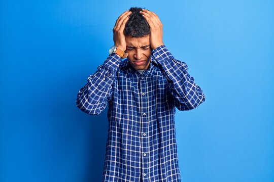 Young african amercian man wearing casual clothes suffering from headache desperate and stressed because pain and migraine. hands on head.