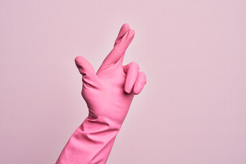 Hand of caucasian young man with cleaning glove over isolated pink background gesturing fingers...