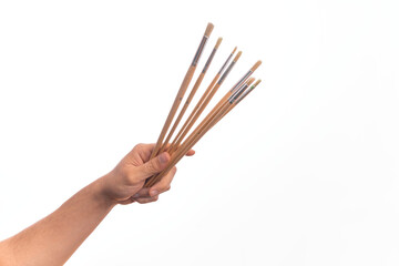 Hand of caucasian young man holding paintbrushes over isolated white background