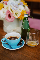 Coffee in a blue cup, sour water and flower box  on the table in the cafe