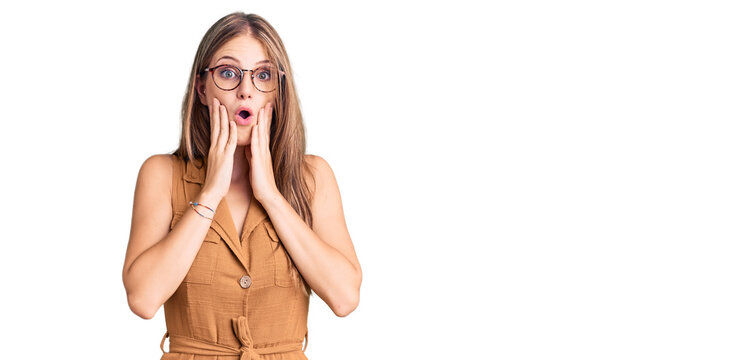 Young beautiful blonde woman wearing casual clothes and glasses afraid and shocked, surprise and amazed expression with hands on face