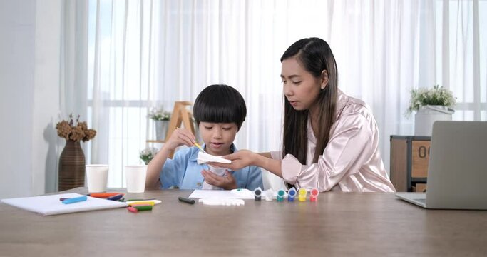 Happy asian mother and little son together paint. Happy mother and daughter are having fun while drawing at home. spends time together lifestyle.