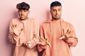 Young gay couple wearing casual clothes disgusted expression, displeased and fearful doing disgust...
