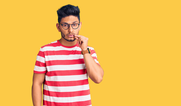 Handsome latin american young man wearing casual clothes and glasses mouth and lips shut as zip with fingers. secret and silent, taboo talking
