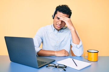 Young handsome hispanic man working at the office wearing operator headset surprised with hand on...