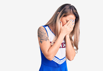 Young beautiful blonde woman wearing cheerleader uniform with sad expression covering face with hands while crying. depression concept.