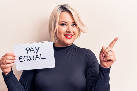 Beautiful plus size woman asking for equality economy holding paper with pay equal message smiling happy pointing with hand and finger to the side
