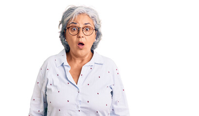 Senior woman with gray hair wearing casual business clothes and glasses scared and amazed with open mouth for surprise, disbelief face