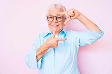 Senior beautiful woman with blue eyes and grey hair wearing glasses smiling making frame with hands and fingers with happy face. creativity and photography concept.