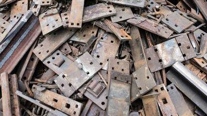 Pile of scrap metal pieces and old rusting railroad ties background. Grungy plates and rusty metal in abandoned pile