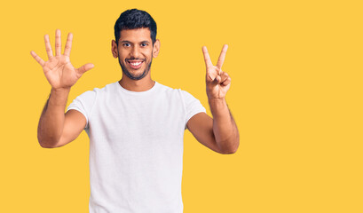 Young latin man wearing casual clothes showing and pointing up with fingers number seven while smiling confident and happy.