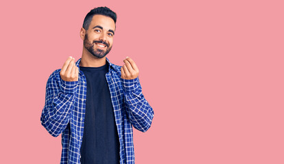 Young hispanic man wearing casual clothes doing money gesture with hands, asking for salary...