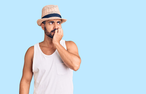 Young hispanic man wearing casual summer hat looking stressed and nervous with hands on mouth biting nails. anxiety problem.