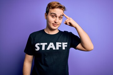 Young handsome redhead worker man wearing staff t-shirt uniform over purple background Smiling pointing to head with one finger, great idea or thought, good memory