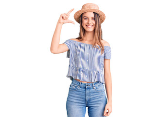 Obraz na płótnie Canvas Young beautiful girl wearing hat and t shirt smiling and confident gesturing with hand doing small size sign with fingers looking and the camera. measure concept.