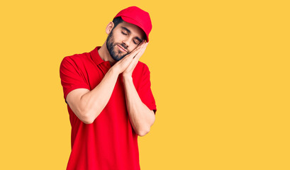 Young handsome man with beard wearing delivery uniform sleeping tired dreaming and posing with hands together while smiling with closed eyes.