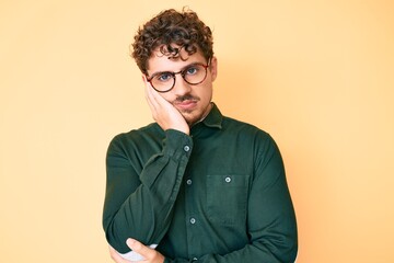 Obraz premium Young caucasian man with curly hair wearing casual clothes and glasses thinking looking tired and bored with depression problems with crossed arms.