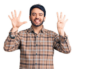 Young hispanic man wearing casual clothes showing and pointing up with fingers number nine while smiling confident and happy.