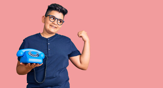 Little boy kid using vintage telephone pointing thumb up to the side smiling happy with open mouth