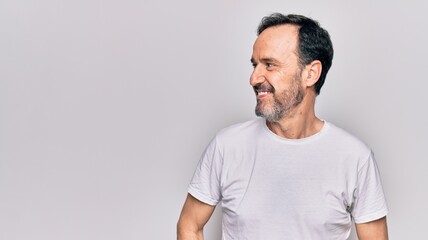 Middle age handsome man wearing casual t-shirt standing over isolated white background looking to side, relax profile pose with natural face and confident smile.