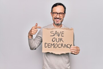 Middle age man holding banner with saver our democracy message over white background smiling happy pointing with hand and finger