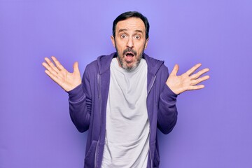 Middle age handsome sporty man wearing casual purple sweatshirt over isolated background clueless...