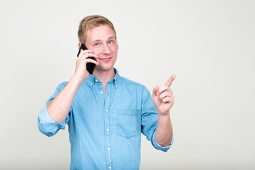 Portrait of young handsome blond businessman talking on the phone