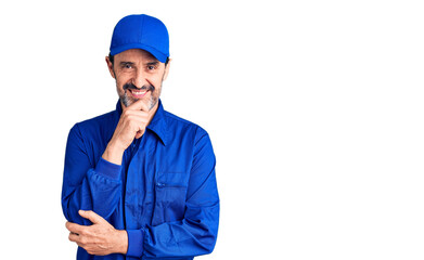 Middle age handsome man wearing mechanic uniform looking confident at the camera smiling with crossed arms and hand raised on chin. thinking positive.