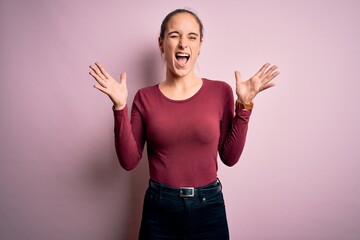 Young beautiful woman wearing casual t-shirt standing over isolated pink background celebrating mad...