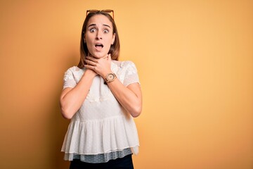 Young beautiful woman wearing casual t-shirt and sunglasses over isolated yellow background shouting and suffocate because painful strangle. Health problem. Asphyxiate and suicide concept.