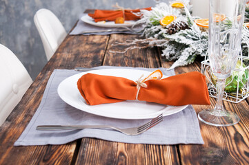 Set table for the new year, orange napkin in a white plate