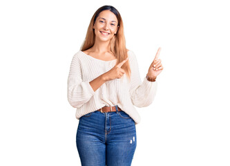 Beautiful young woman wearing casual clothes smiling and looking at the camera pointing with two hands and fingers to the side.