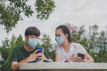 Asian Boy and  Girl in face mask using mobile smartphone,Concept new normal social distancing