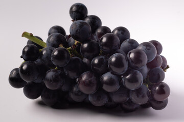 Black grapes without seeds in a rattan basket. White background