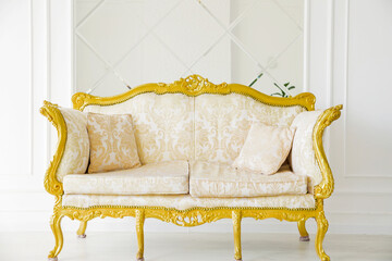 Luxurious golden sofa on a background of old white wall